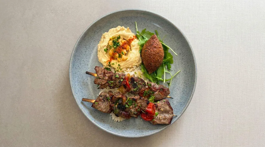 Grilled beef skewers with hummus, kibbeh and rice, plated for catering