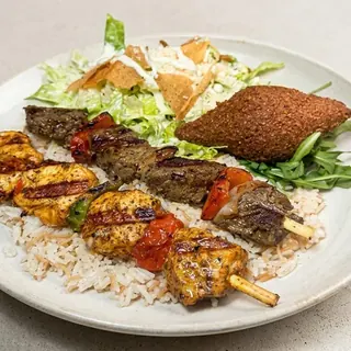 Mixed grill plate with chicken and beef skewers over rice